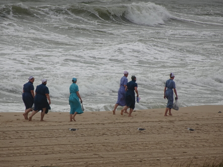 Amish ladies walking in the surf